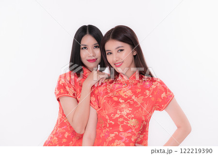 Two women in traditional red dresses pose stylishly against a white background. Two women in traditional red dresses pose stylishly against a white background. 122219390