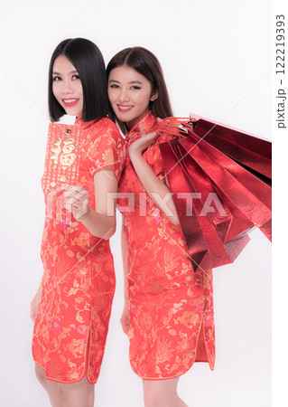 Two women wearing traditional red dresses celebrate cultural heritage joyfully. Two women wearing traditional red dresses celebrate cultural heritage joyfully. 122219393