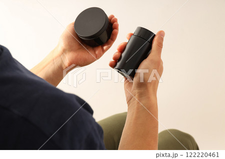 Cosmetics bottle and jar in male hands on white background, close up 122220461
