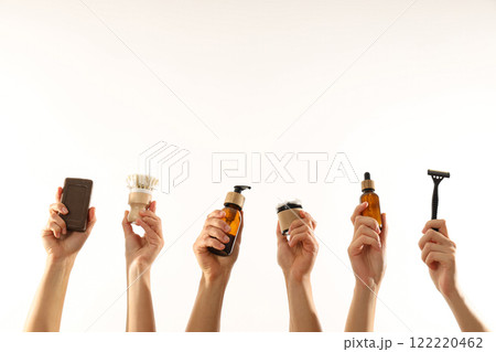Men's shaving tools and cosmetics bottles in hands on white background, space for text 122220462