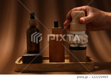 Men's shaving tools, soap, cosmetics bottles and hand on brown background 122220465