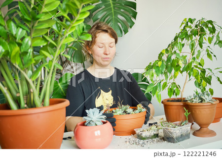Woman gardening indoors with potted plants and succulents 122221246