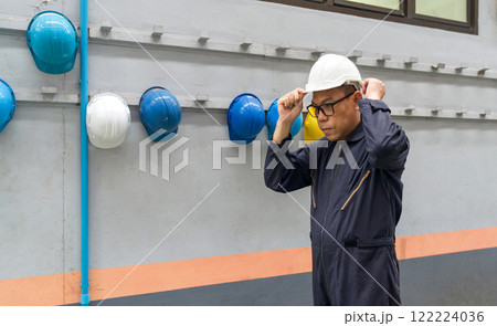 Asian man in mechanic coverall dust protection suit, wearing construction hardhat on his head for safety. Concept of work safety. Building industry. Asian man in mechanic coverall dust protection suit, wearing construction hardhat on his head for safety. Concept of work safety. Building industry. 122224036
