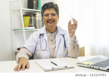 Senior female doctor holding ATK kit in hospital room, covid19 and pandemic concept. Senior female doctor holding ATK kit in hospital room, covid19 and pandemic concept. 122224763