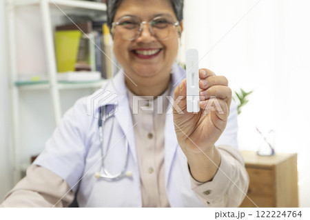 Senior female doctor holding ATK kit in hospital room, covid19 and pandemic concept. Senior female doctor holding ATK kit in hospital room, covid19 and pandemic concept. 122224764