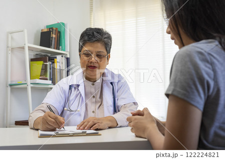 General practitioner taking notes when talking to female patient in hospital. General practitioner taking notes when talking to female patient in hospital. 122224821