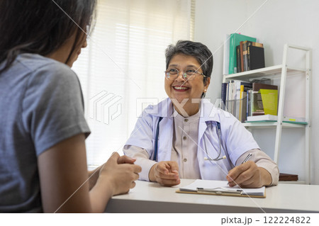 General practitioner taking notes when talking to female patient in hospital. General practitioner taking notes when talking to female patient in hospital. 122224822