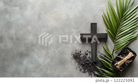 Cross is on a grey background with a palm leaf and some dirt 122225091