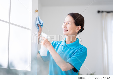 窓を掃除するシニア女性のハウスキーパー 122226252