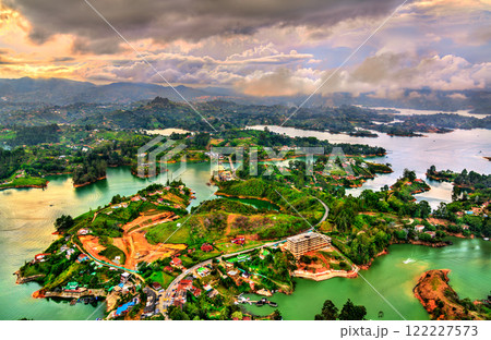 Aerial view of Guatape, Colombia at sunset, showcasing its vibrant landscapes lush green hills and a network of shimmering turquoise lakes 122227573