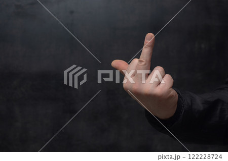 Man in a shirt showing a crude fuck gesture, middle finger sign, close-up against a concrete wall. Man in a shirt showing a crude fuck gesture, middle finger sign, close-up against a concrete wall. 122228724