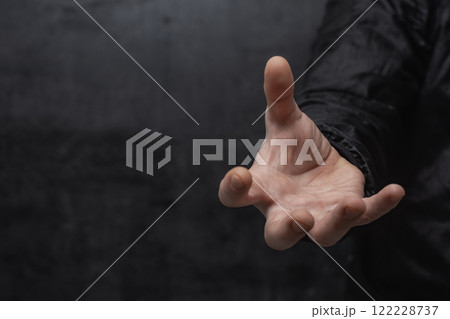Close-up of a man in a shirt, making a hand grip with open palm against a concrete wall. Close-up of a man in a shirt, making a hand grip with open palm against a concrete wall. 122228737