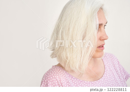 Caucasian mature woman with white hair in polka dot shirt looking sideways Caucasian mature woman with white hair in polka dot shirt looking sideways 122228811