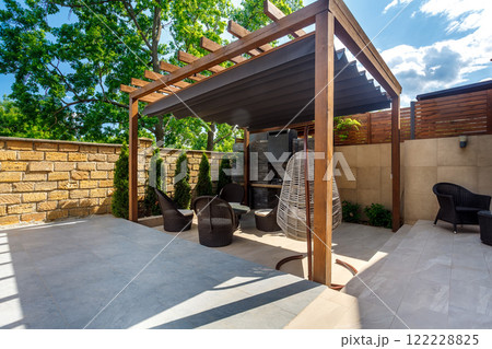Backyard outdoor bbq zone with pergola, fireplace and hanging chair. Summer party place 122228825