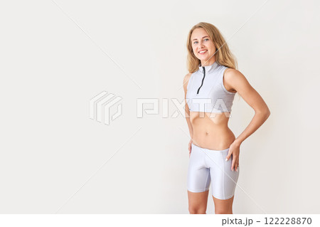 Young caucasian female in athletic wear smiling confidently against a minimalist 122228870