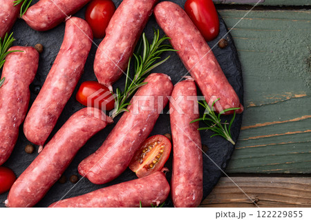 Raw beef sausages with rosemary and tomatoes photography . Top view 122229855