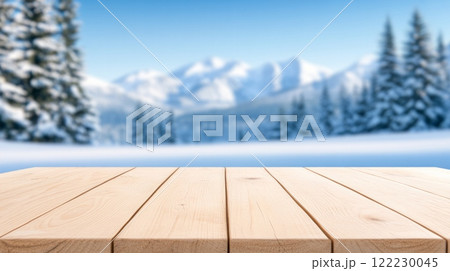 Empty wooden table in the foreground with a snowy winter landscape of pine trees and mountains in the background 122230045