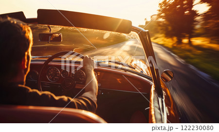 Man enjoying a trip behind the wheel of a retro convertible, surrounded by soft golden light of nature, selective focus on the steering wheel and the man's hands. 122230080