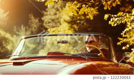 Man driving stylish red convertible against blurred nature background, concept of traveling by retro car on Italian roads 122230083