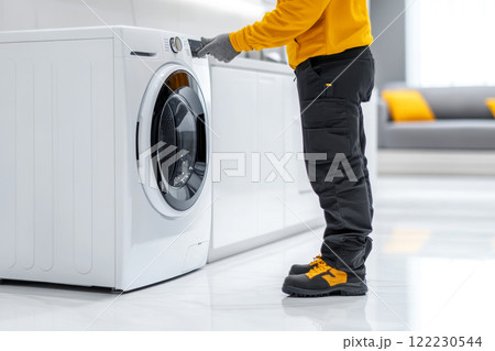 A man in work clothes professionally inspects household appliances installed at a client's house, copy space about services for service and maintenance of equipment A man in work clothes professionally inspects household appliances installed at a client's house, copy space about services for service and maintenance of equipment 122230544