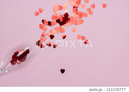 Creative representation of a wineglass spilling shimmering red sequins against a pastel pink backdrop. Ideal for themes of celebration, romance, minimalism, and modern aesthetics valentines 122230777
