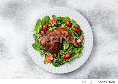 Grilled chicken legs with tomatoes and salad . Top view Grilled chicken legs with tomatoes and salad . Top view 122231020