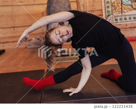 A yoga teacher shows students how to do an asana correctly. A young woman teaches yoga and helps with poses during a class in a spacious studio 122231438