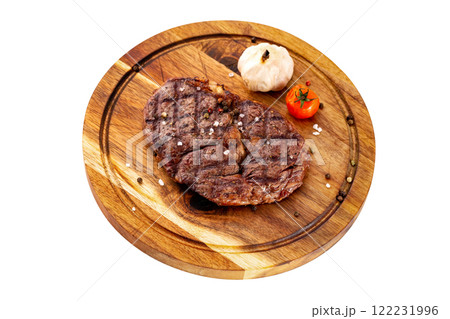 Ribeye steak served with tomato and garlic at a wooden board isolated at white background. Ribeye steak served with tomato and garlic at a wooden board isolated at white background. 122231996