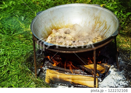 Closeup image of meat stewed in old cauldron at outdoors bonfire Closeup image of meat stewed in old cauldron at outdoors bonfire 122232108