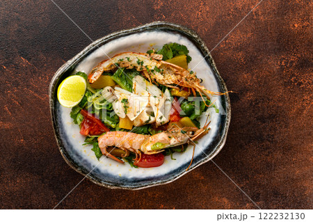 Plate of fresh salad with shrimps and tomatoes at concrete background. 122232130