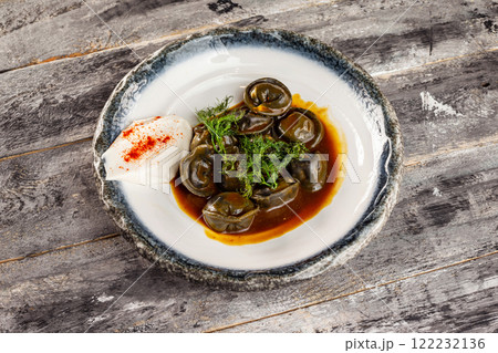 Plate of russian meal pelmeni with beef served with sour cream at wooden rustic table background. Black dumplings. Plate of russian meal pelmeni with beef served with sour cream at wooden rustic table background. Black dumplings. 122232136