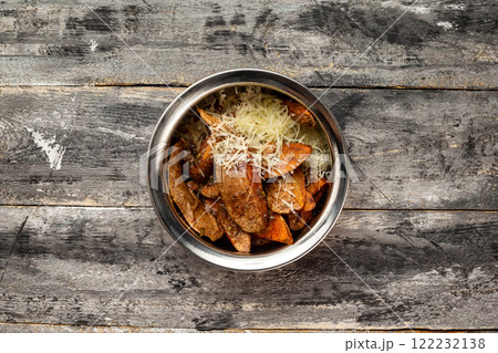Bowl of baked potatoes slices with cheese at rustic wooden table background. Bowl of baked potatoes slices with cheese at rustic wooden table background. 122232138