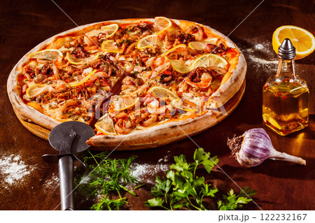Italian pizza with lemon, cheese and seafood at rustic wooden desk background. Closeup image 122232167