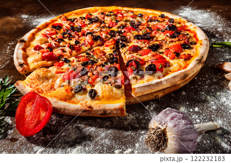 Closeup image of tasty italian pizza with cheese, tomato, olives and ham at wooden board background. 122232183