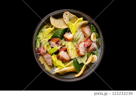 Top view image of caesar salad served in an iron pan isolated at black background. Top view image of caesar salad served in an iron pan isolated at black background. 122232230