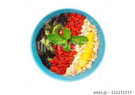 Top view image of healthy vegan detox dessert. Bowl of smoothie with kiwi, mango, oats, goji berries and chia seeds isolated at white background. Top view image of healthy vegan detox dessert. Bowl of smoothie with kiwi, mango, oats, goji berries and chia seeds isolated at white background. 122232247
