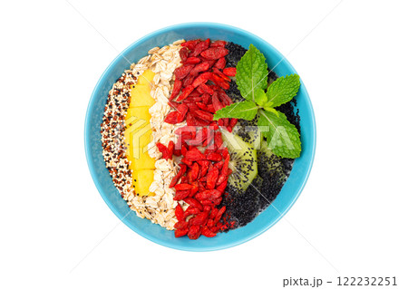 Closeup image of sweet superfood detox dessert as healthy lifestyle concept. Bowl of smoothie with kiwi, mango, oats, goji berries and chia seeds isolated at white background. 122232251