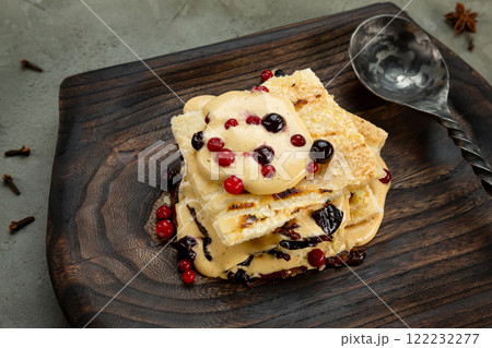 Closeup image of millefeulle with prunes and wild berries served with a spoon at wooden tray at concrete background. Closeup image of millefeulle with prunes and wild berries served with a spoon at wooden tray at concrete background. 122232277