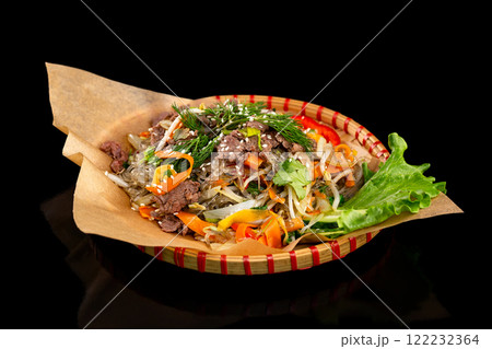 Wicker plate of traditional vietnamese dish - glass noodles with beef meat and vegetables isolated at black background. 122232364