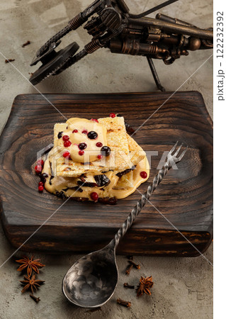 Vertical image of millefeulle with prunes and wild berries served with a spoon at wooden tray at concrete background. Vertical image of millefeulle with prunes and wild berries served with a spoon at wooden tray at concrete background. 122232392