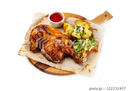 Roasted chicken legs served with potato and tomato sauce on paper at wooden tray isolated at white background. 122232457