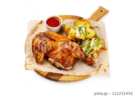 Roasted chicken legs served with potato and tomato sauce on paper at wooden tray isolated at white background. 122232458