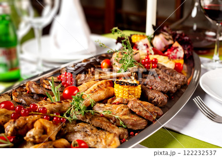 Metal dish with grilled meat set of beef tongue, pork, chicken, sausages and vegetables at decorated table background. Metal dish with grilled meat set of beef tongue, pork, chicken, sausages and vegetables at decorated table background. 122232537