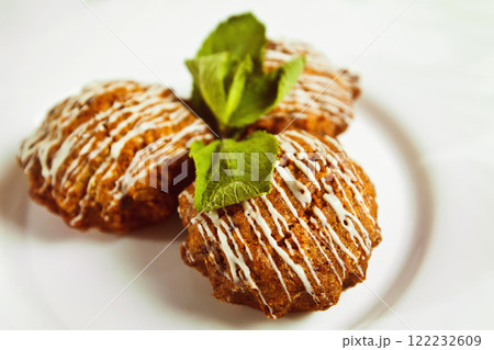 Closeup image of tasty brown muffins decorated with fresh mint leafs isolated at white background. 122232609