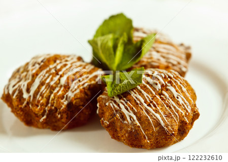 Closeup image of tasty brown muffins decorated with fresh mint leafs isolated at white background. Closeup image of tasty brown muffins decorated with fresh mint leafs isolated at white background. 122232610
