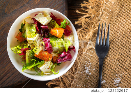 Fresh diet vegeterian salad decorated with herbs on wooden tray at table background. 122232617