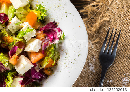 Fresh diet vegeterian salad decorated with herbs on wooden tray at table background. 122232618