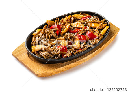 Steel pan with traditional Japanese dish - buckwheat noodles with chicken and vegetables served with teriyaki sauce at wooden board isolated at white background. Steel pan with traditional Japanese dish - buckwheat noodles with chicken and vegetables served with teriyaki sauce at wooden board isolated at white background. 122232738