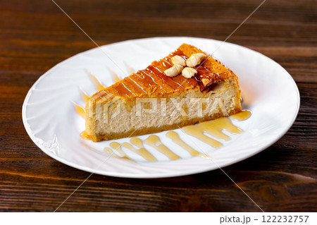 Closeup slice of cheesecake decorated with maple syrup at wooden board background. Closeup slice of cheesecake decorated with maple syrup at wooden board background. 122232757