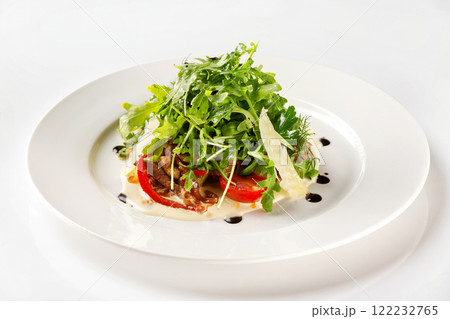 Plate of beef salad served with parmesan, green and tomato isolated at white background. 122232765